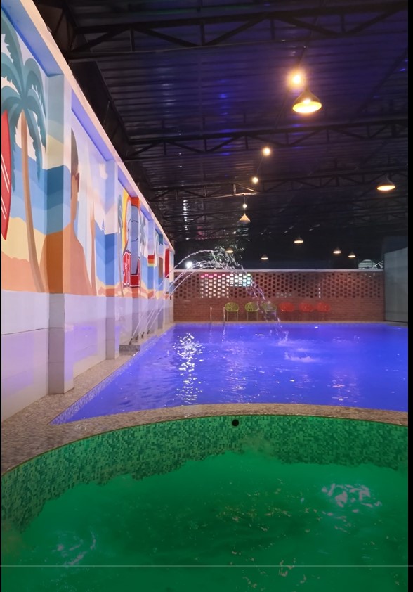 Nexora Structure Limited Indore Swimming Pool With Colourful Wall Art And Water Fountain At Night